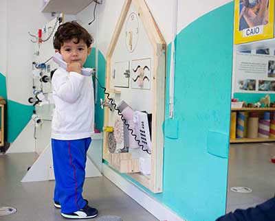 Criança interagindo no telefone na parede criativa - Educação Infantil Uniepre