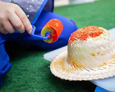Criança pintando peça junina decorativa - Educação Infantil Uniepre