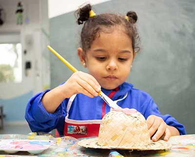 Criança pintando peça decorativa junina - Educação Infantil Uniepre