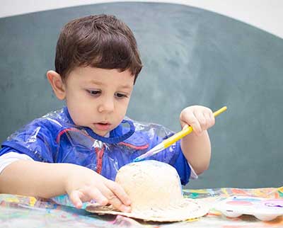 Criança pintando peça decorativa junina - Educação Infantil Uniepre