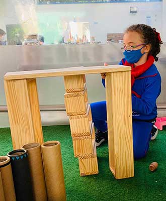 Criança construíndo e posicionando blocos de madeira - Ensino Fundamental Uniepre